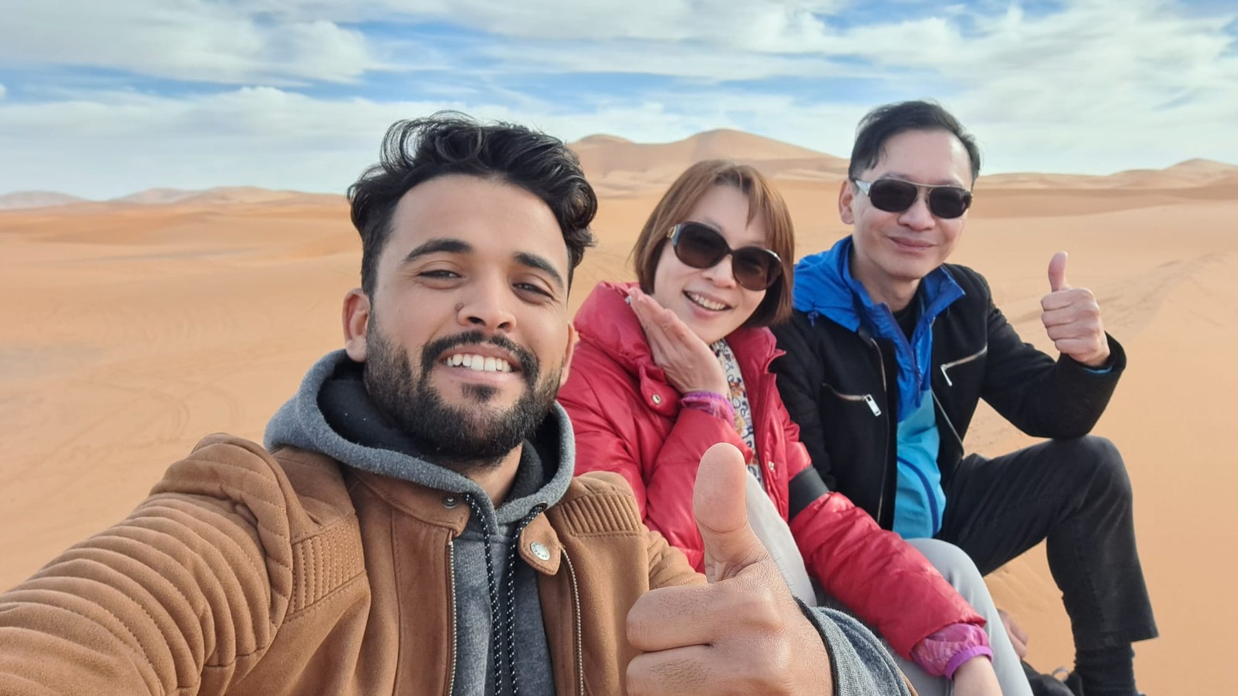 Local host taking a desert selfie with two guests in Erg Chebbi