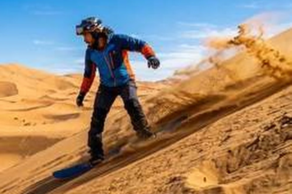 Traveler sandboarding on an Erg Chebbi dune near Merzouga